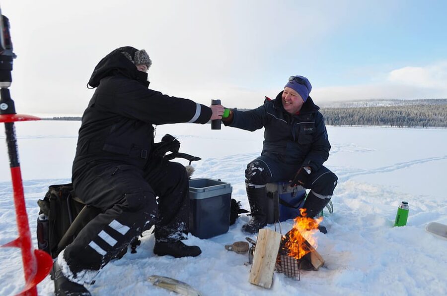 Ice fishing program in Lapland - The fire, blankets, and warm berry juice